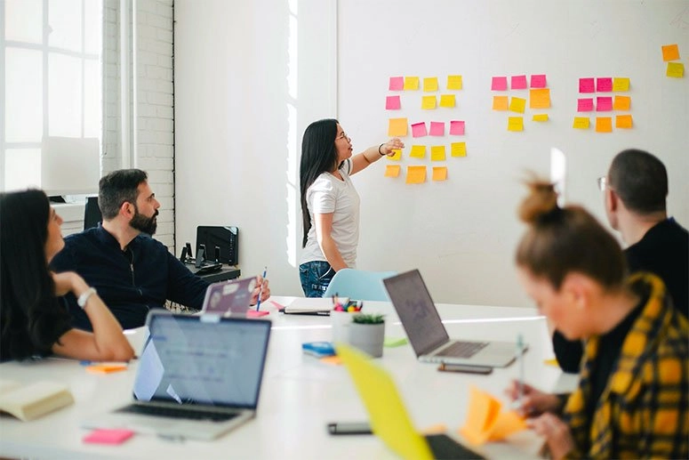 Woman placing sticky notes on a wall at a business meeting